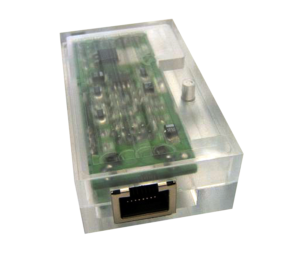 Transparente rechteckige Kunststoffbox, die eine grüne Leiterplatte mit elektronischen Bauteilen zeigt, mit einem metallisch umrahmten Anschluss an der Vorderseite.