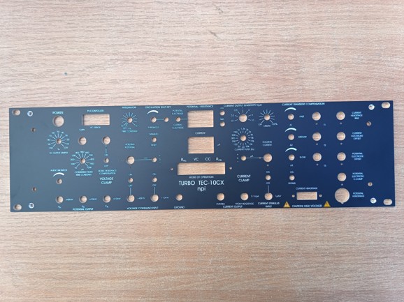 Blaues Schaltpanel mit vielen Reglern und Anzeigen auf einer Holzoberfläche