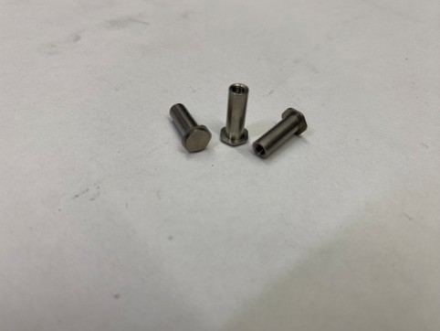 Drei metallische Gewindehülsen auf einer hellen Oberfläche