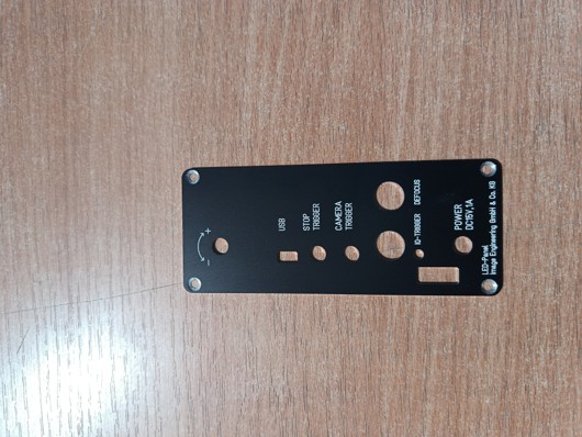 Schwarze Frontplatte mit mehreren Bohrungen und Beschriftungen wie USB, STOP, POWER, CAMERA, ALARM, VOLUME und IR-SENSOR