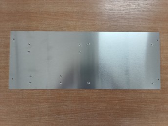 Aluminium-Montageplatte mit mehreren Bohrungen auf Holztisch liegend