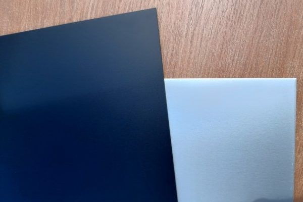 Zwei überlappende Metallplatten auf einer Holzoberfläche, eine dunkelblau und eine silbern