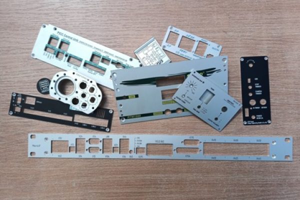 Mehrere Frontplatten und Blenden aus Metall auf einem Holztisch ausgebreitet